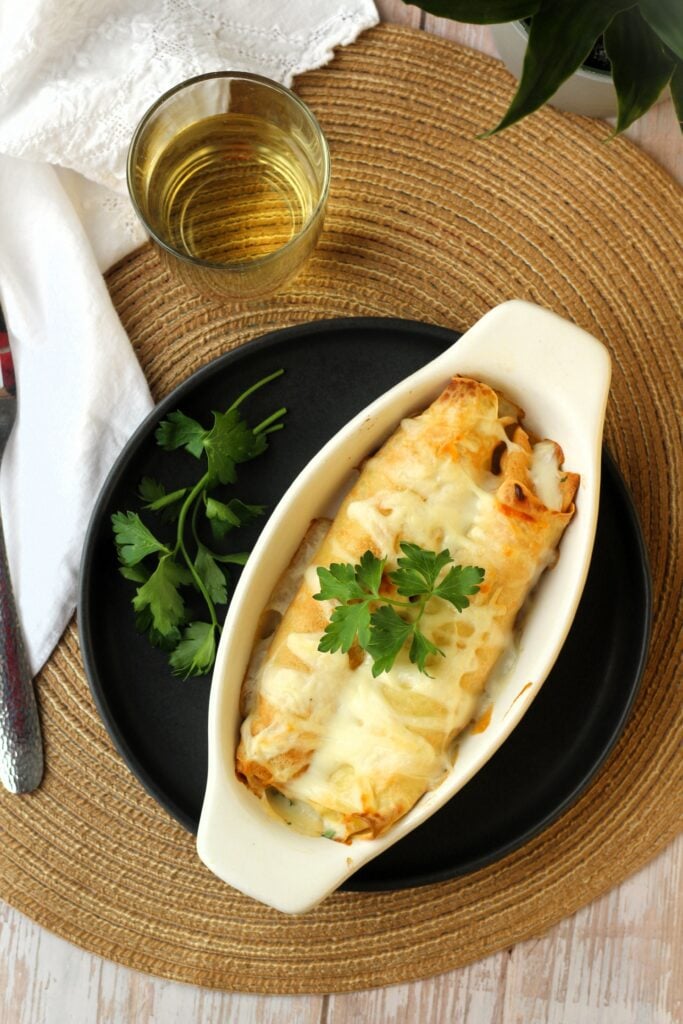 Seafood Crepes Recipe with Béchamel Sauce in au gratin baking dish with parsley.