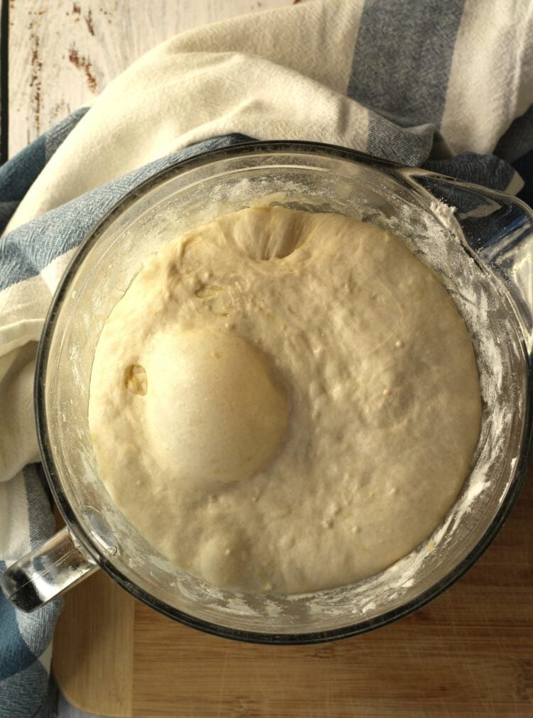 Risen bread dough in glass bowl.