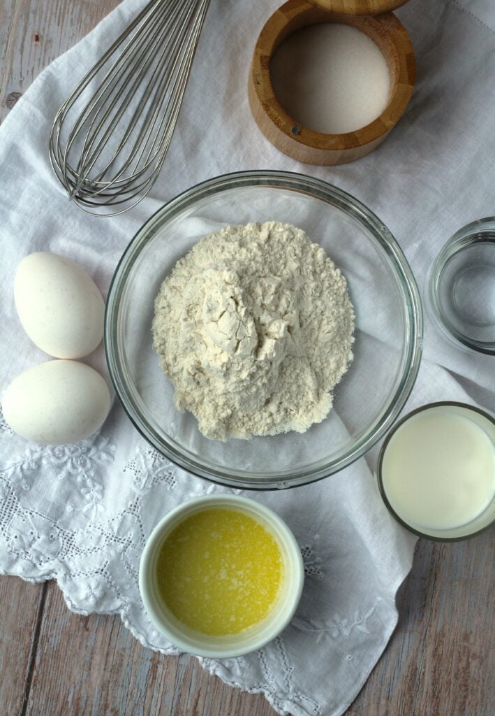 Bowl of flour, milk, butter, salt, melted butter and eggs.