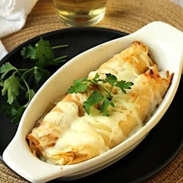 Shrimp and scallop filled crepes topped with bechamel sauce in baking dish.