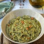Bowl of macco di fave, Siiclian fava bean soup, with spoon, olive oil oil bottle and bread on side.