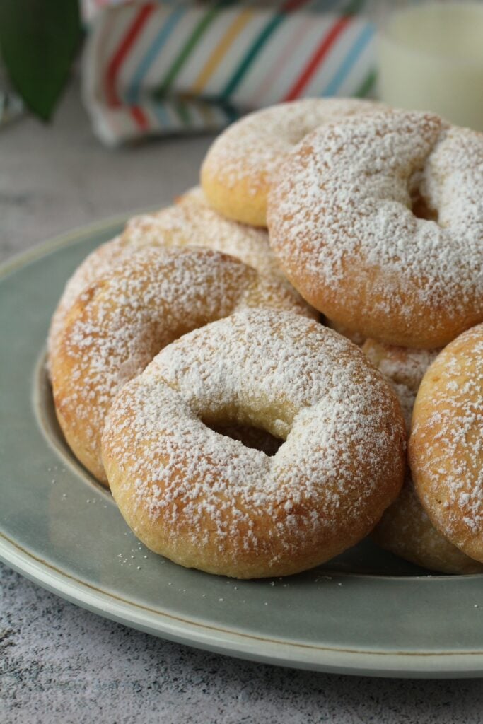 Ricotta ring cookies dusted with powdered sugar on blue plate.