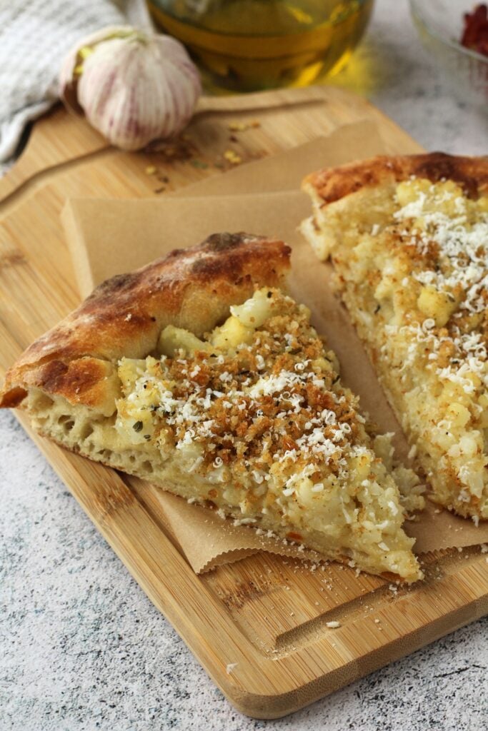 2 slices pizza with cauliflower topping on wood board.