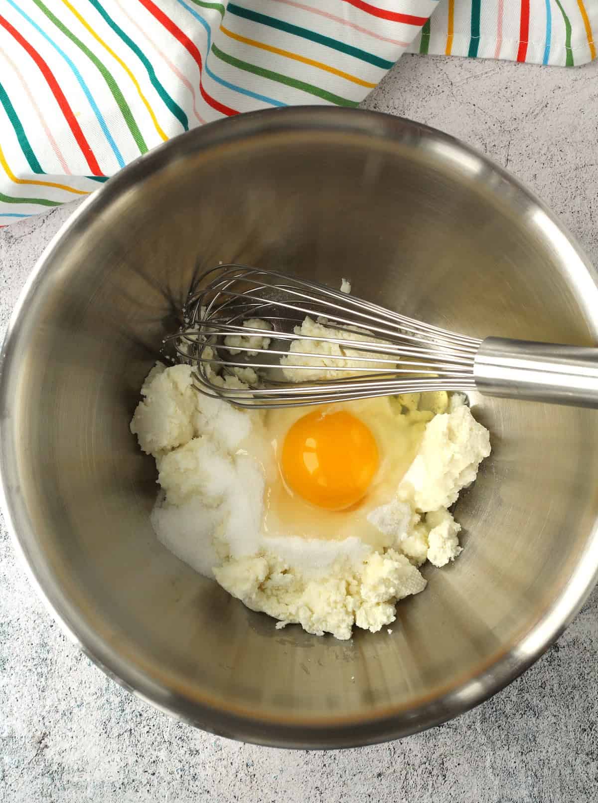 Mixing bowl with ricotta, egg and sugar and whisk.