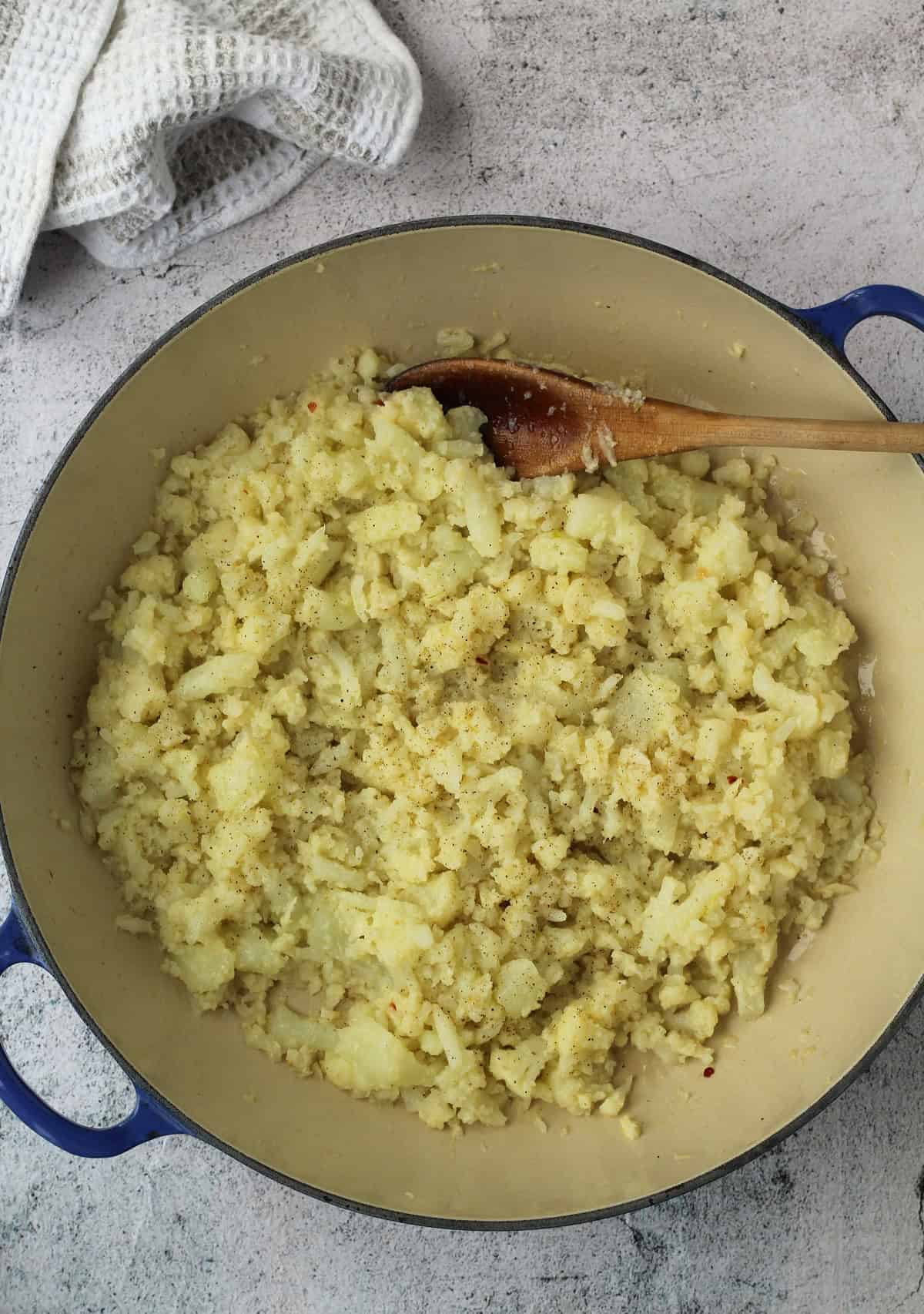 Sautéed cauliflower with garlic in skillet for pizza topping.