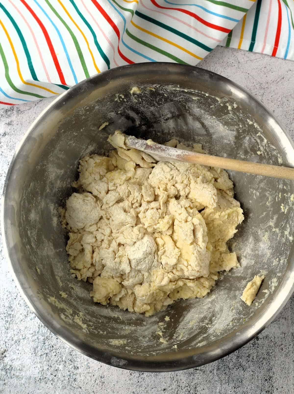 Ricotta ring cookie dough in mixing bowl with wooden spoon.
