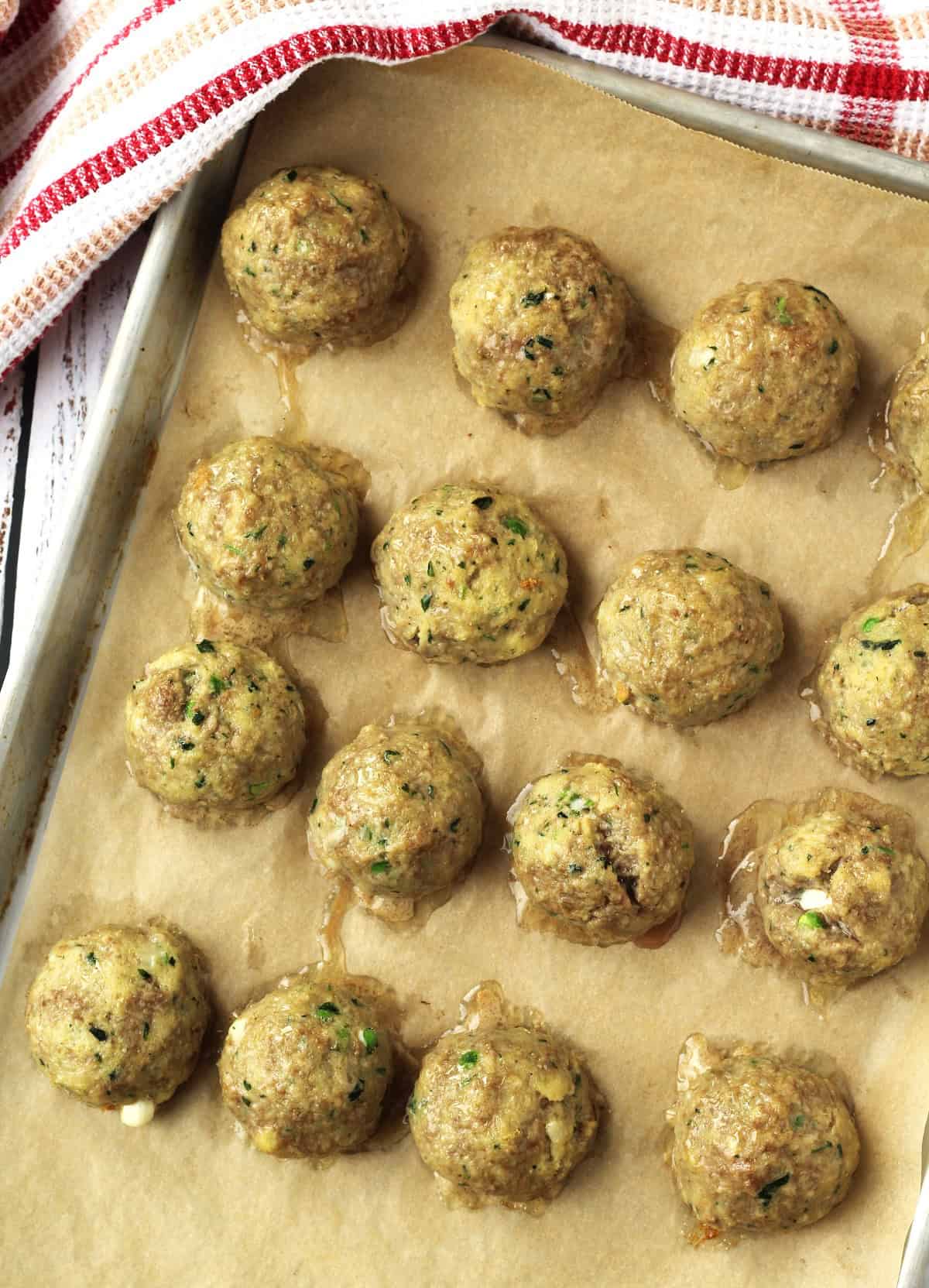 Baked stuffed meatballs on baking sheet.