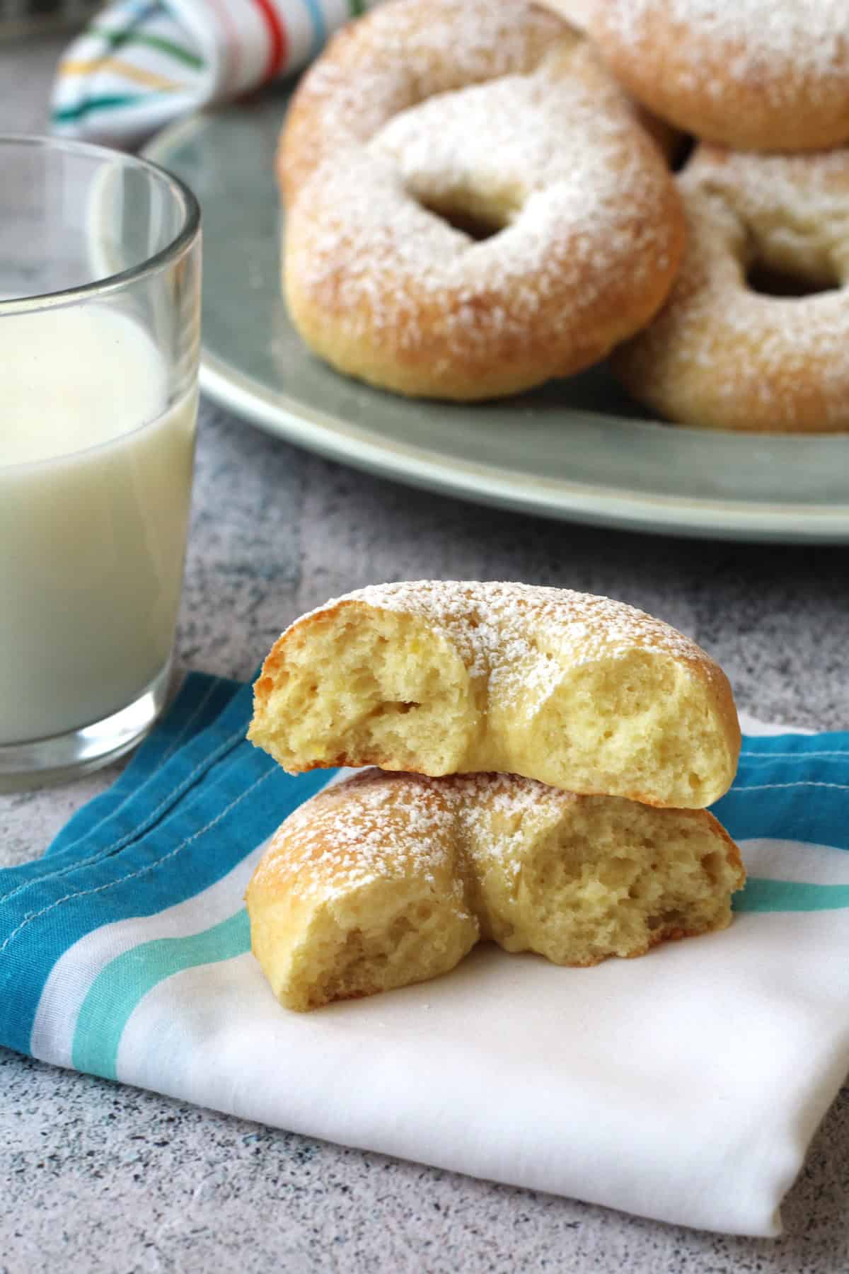 Ricotta ring cookie cut in half on napkin with plate full of cookies behind it.