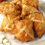 Cipolline Catanesi, onion puff pastry tarts piled on wood board.