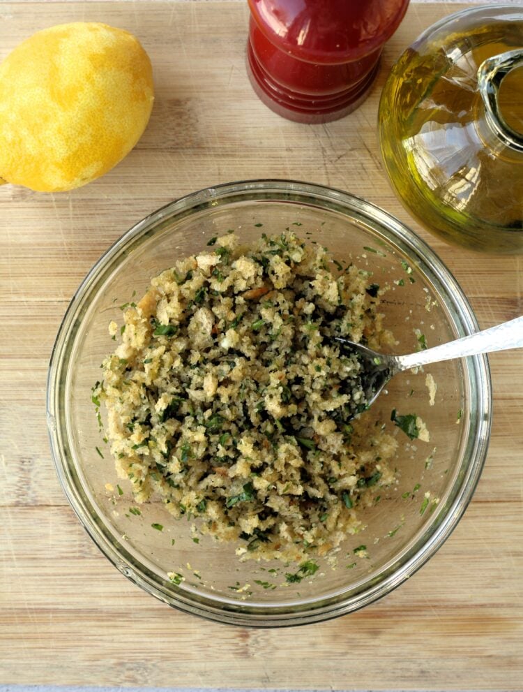 Breadcrumbs tossed with lemon zest, garlic and olive oil in bowl.