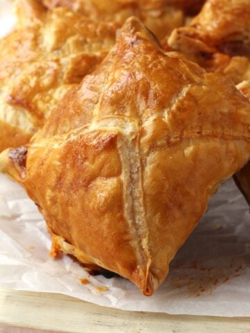 Cipolline Catanesi, or Sicilian onion puff pastry tart on wood board.