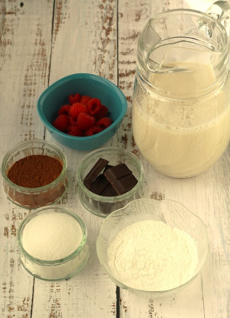 Pitcher of milk, bowls of sugar, cornstarch, cocoa, chocolate and berries.