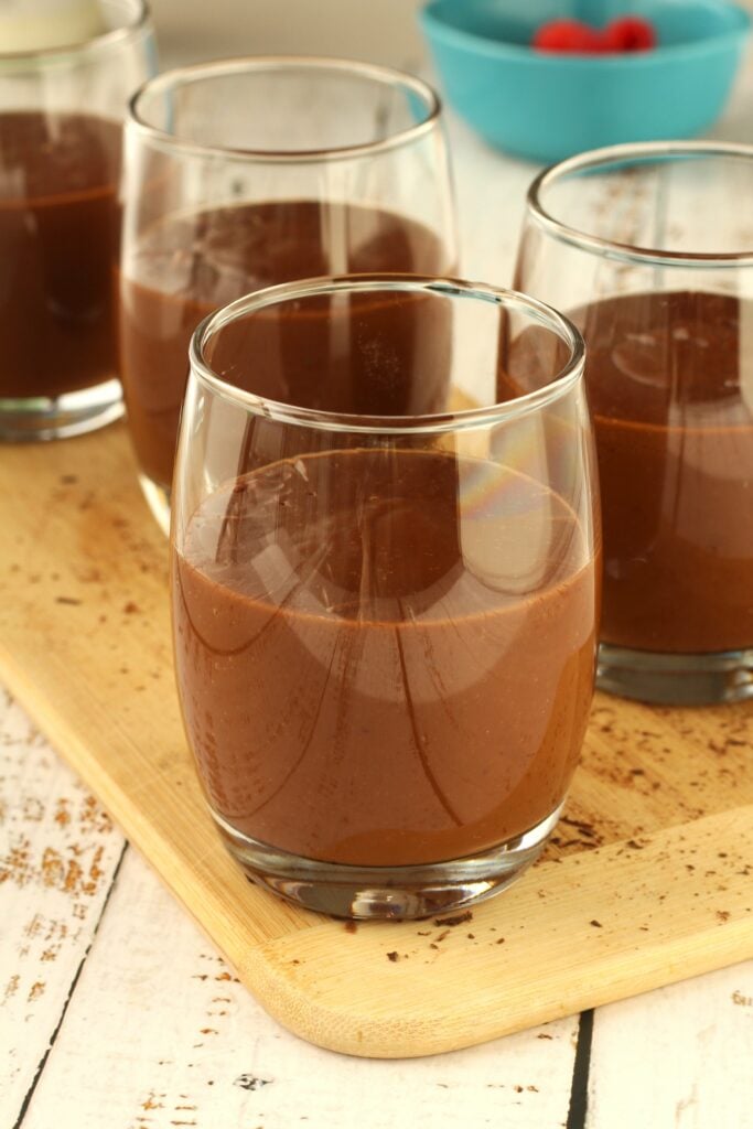 Chocolate pudding poured into glasses on wood board.