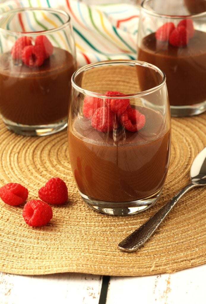 Glasses of chocolate almond milk pudding, or  biancomangiare al cioccolato, topped with berries.