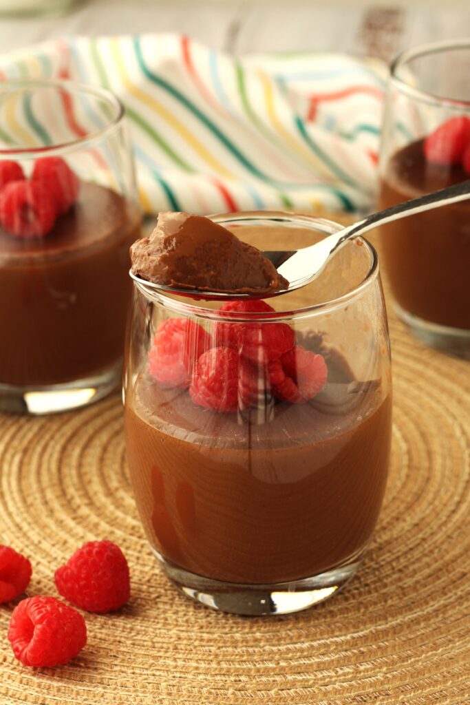 Chocolate biancomangiare, or almond milk chocolate pudding, in glasses topped with berries.