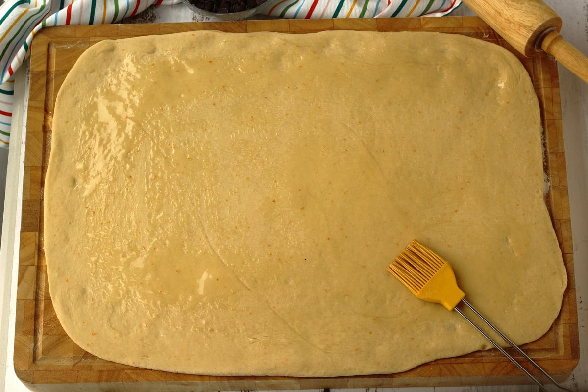 Brioche dough flattened into a rectangle and brushed with butter for chocolate chip bread.