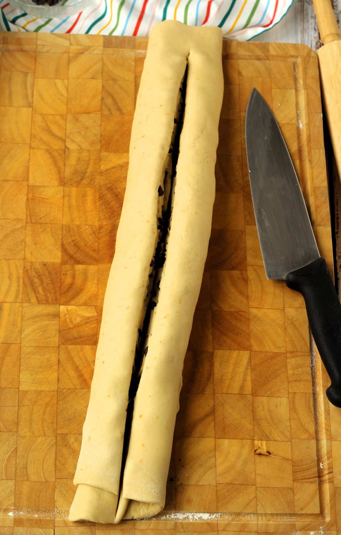 Cylinder shaped chocolate chip brioche bread dough cut in half lengthwise.