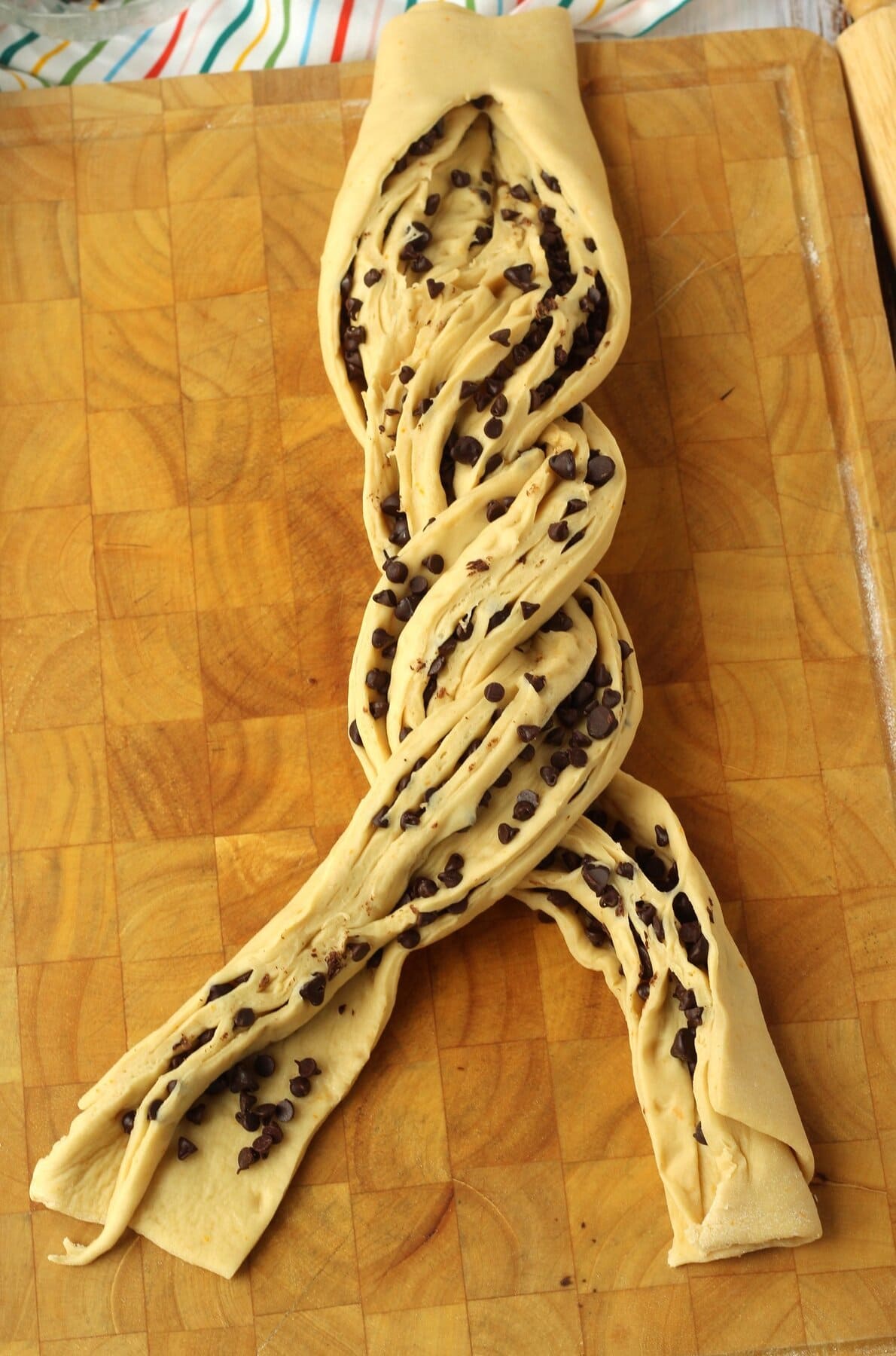 Chocolate chip brioche bread dough lengths twisted together.