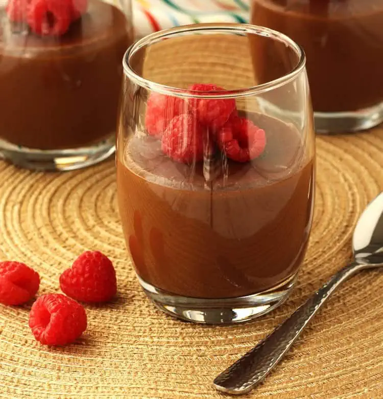 Almond milk chocolate pudding in glasses topped with raspberries.