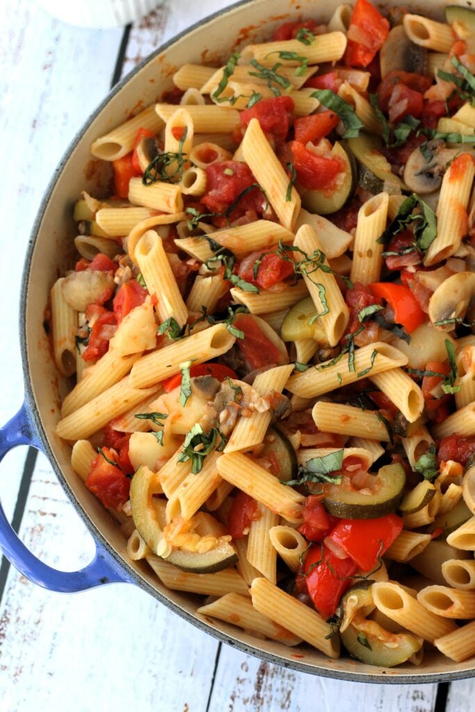 Overhead view of skillet filled with pasta with vegetables and tomato sauce.
