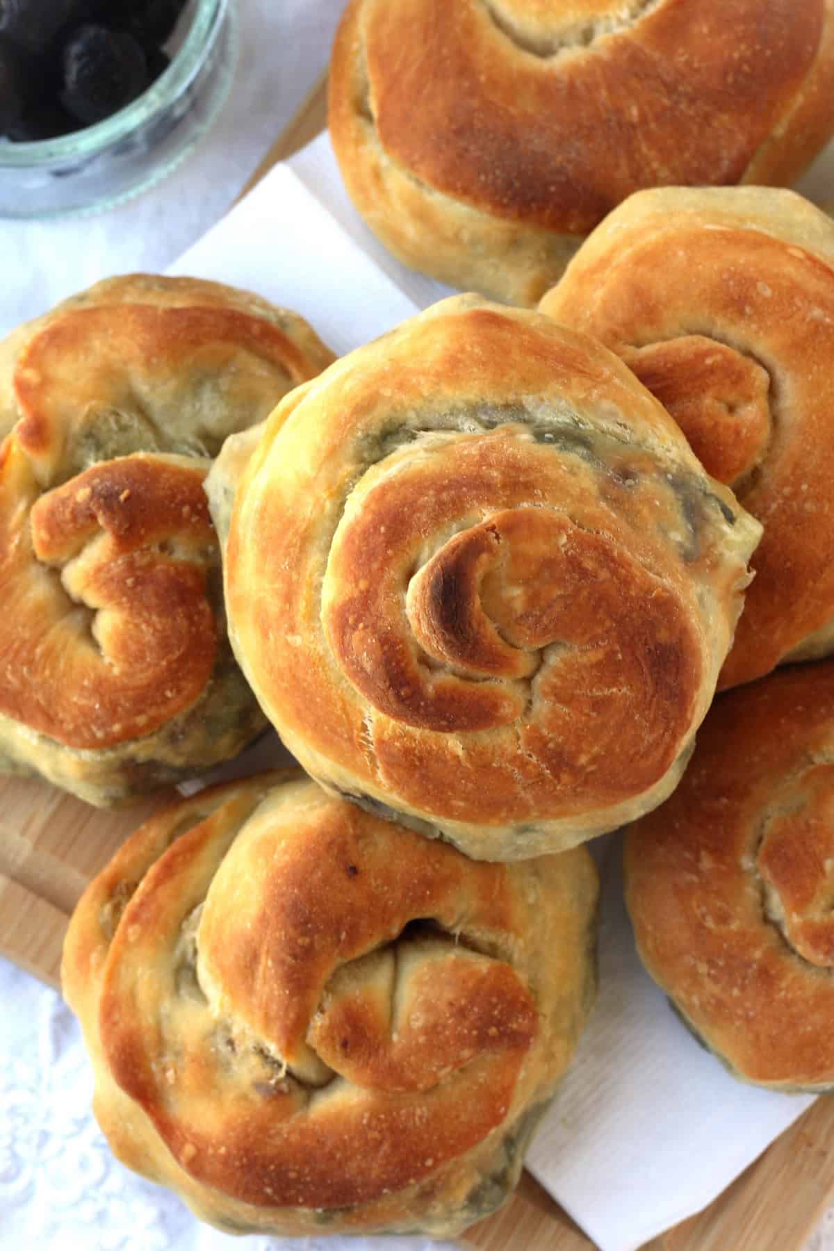 Sicilian bignolati (pizza rolls) filled with swiss chard and potato piled on wood board.