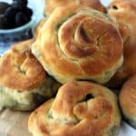 Swiss chard and Potato filled bignolati rolls piled on wood board.