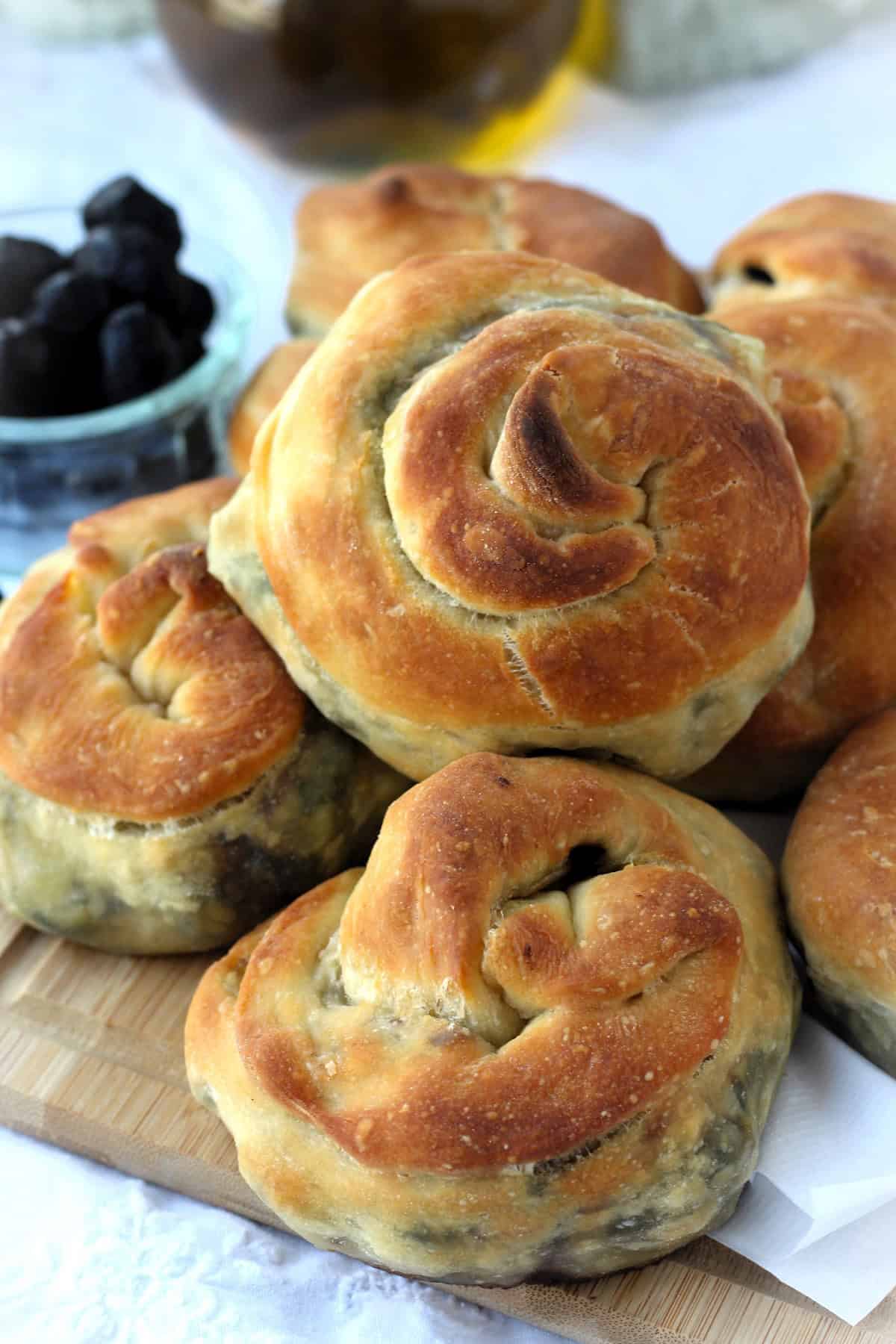 Swiss chard and Potato filled bignolati rolls piled on wood board.