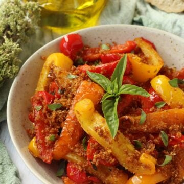 Sicilian peppers with breadcrumbs topped with basil in bowl.