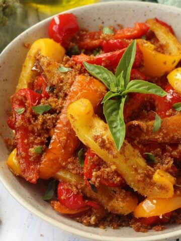 Sicilian peppers with breadcrumbs topped with basil in a bowl.