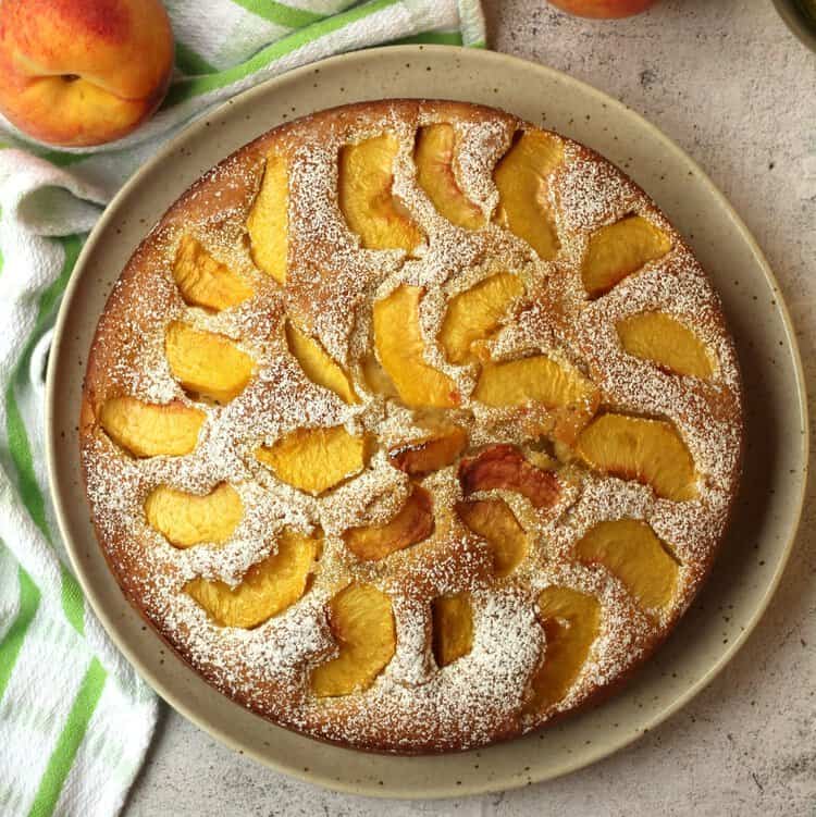 Overhead view of fresh peach cake with powdered sugar on top.
