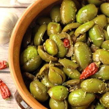 Sicilian cracked green olives seasoned in earthenware bowl.