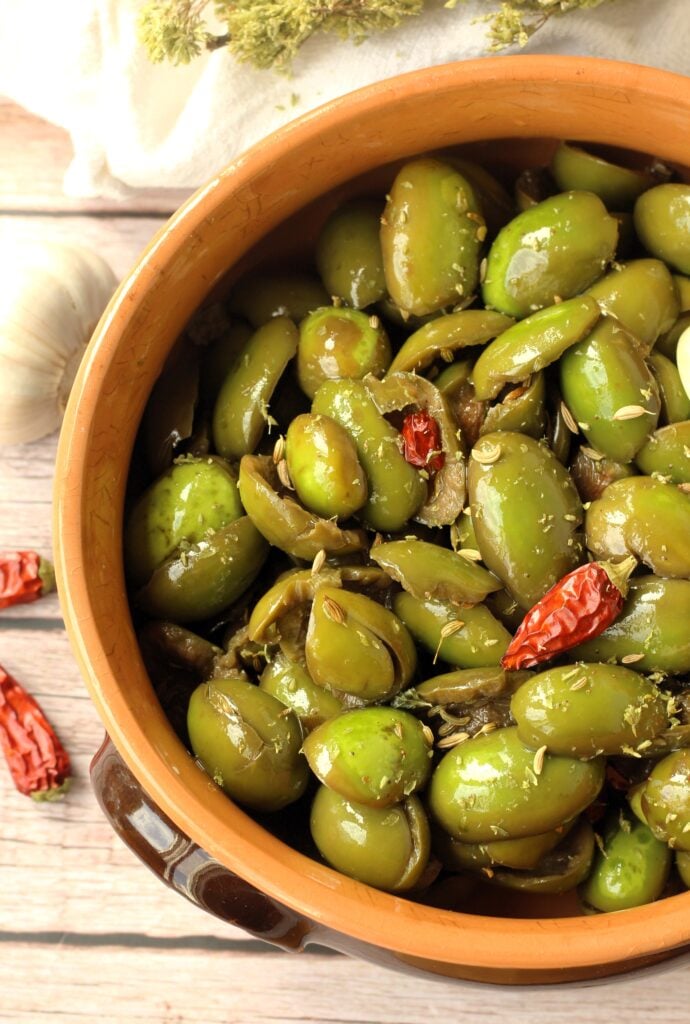 Sicilian cracked green olives seasoned in earthenware bowl.