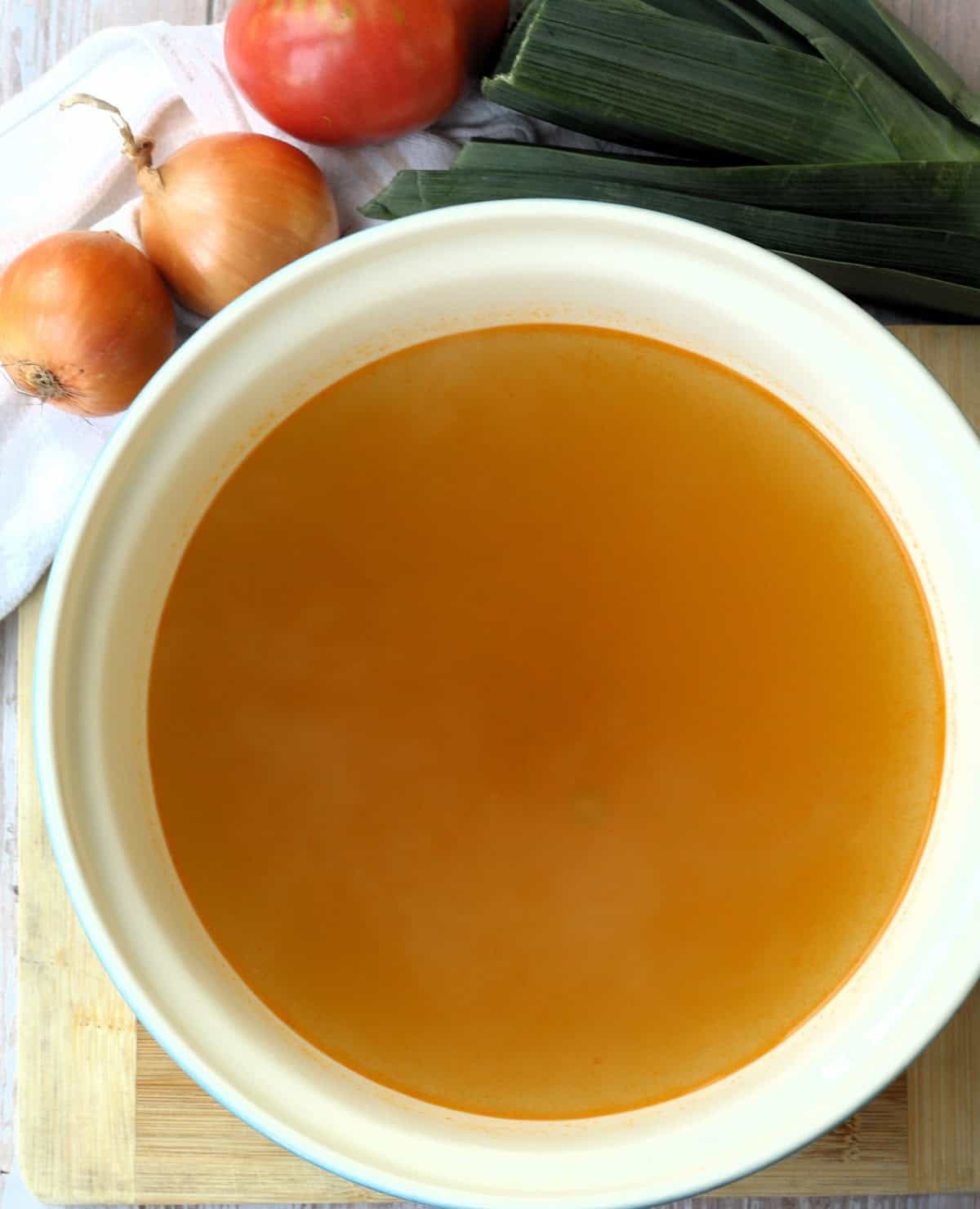 Homemade vegetable broth cooling in large bowl.