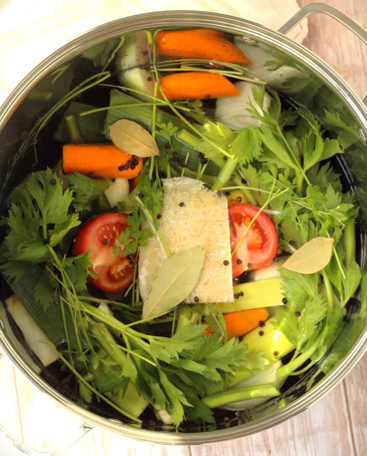 Simmering vegetables and Parmesan rind in stock pot for making vegetable broth.
