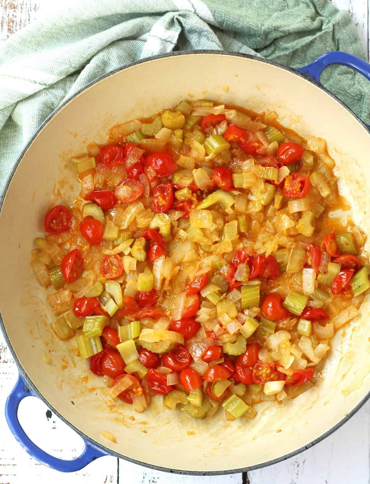 Halved cherry tomatoes in skillet with onion and celery for swordfish caponata.