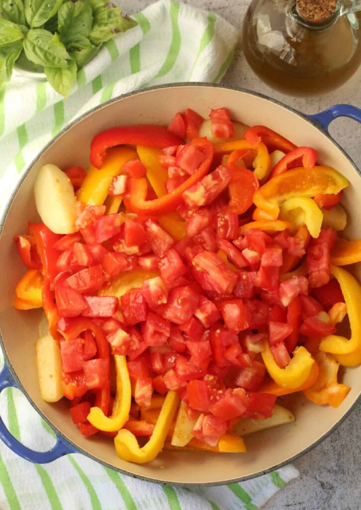 Diced tomatoes added to pan with peppers, potatoes and onions for peperonata.