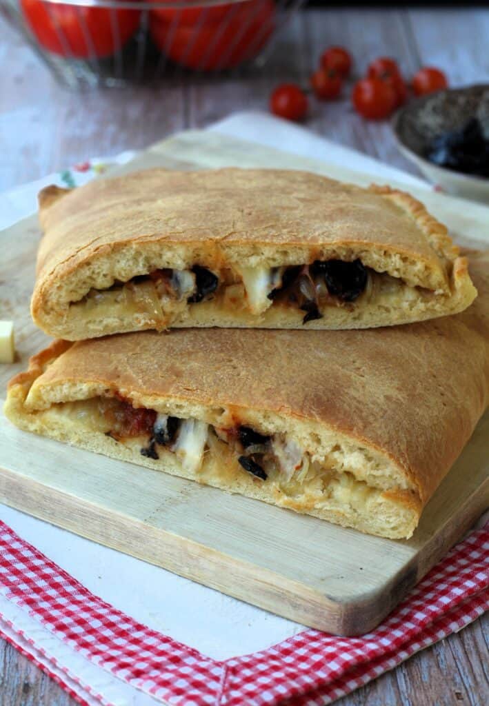 Cudduruni, Sicilian stuffed pizza, halved on wood board.