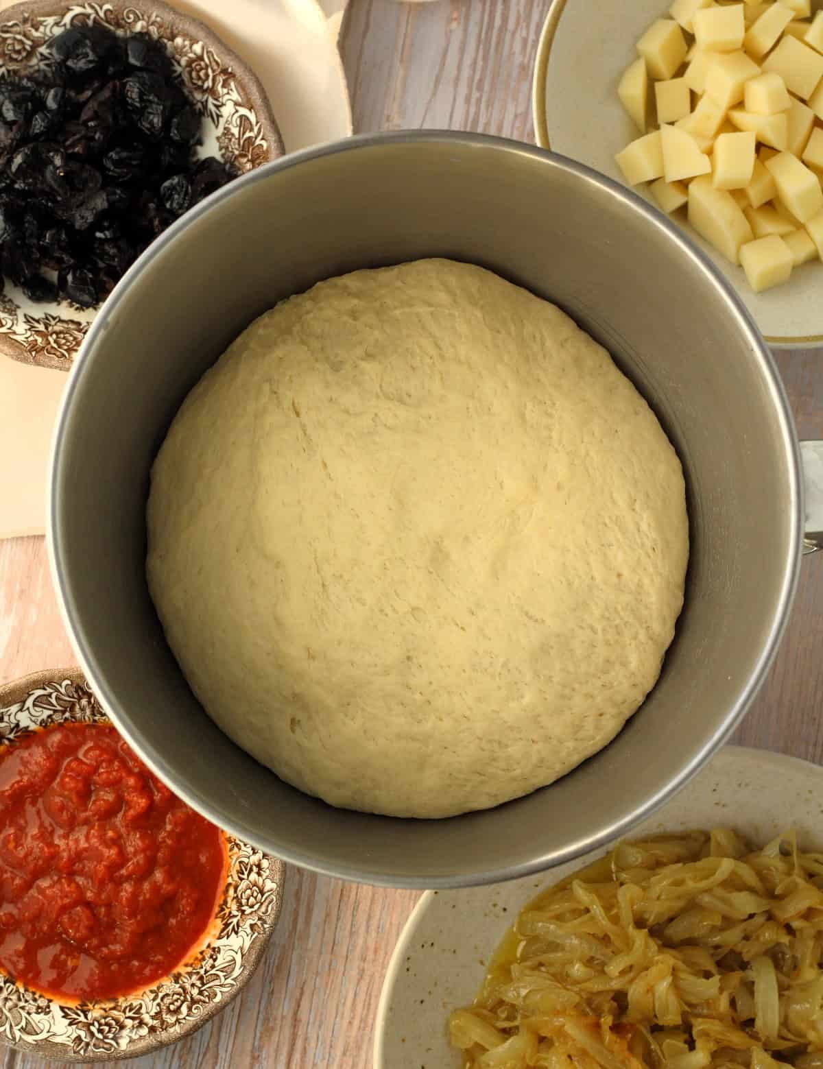 Proofed cudduruni pizza dough in bowl of food processor.