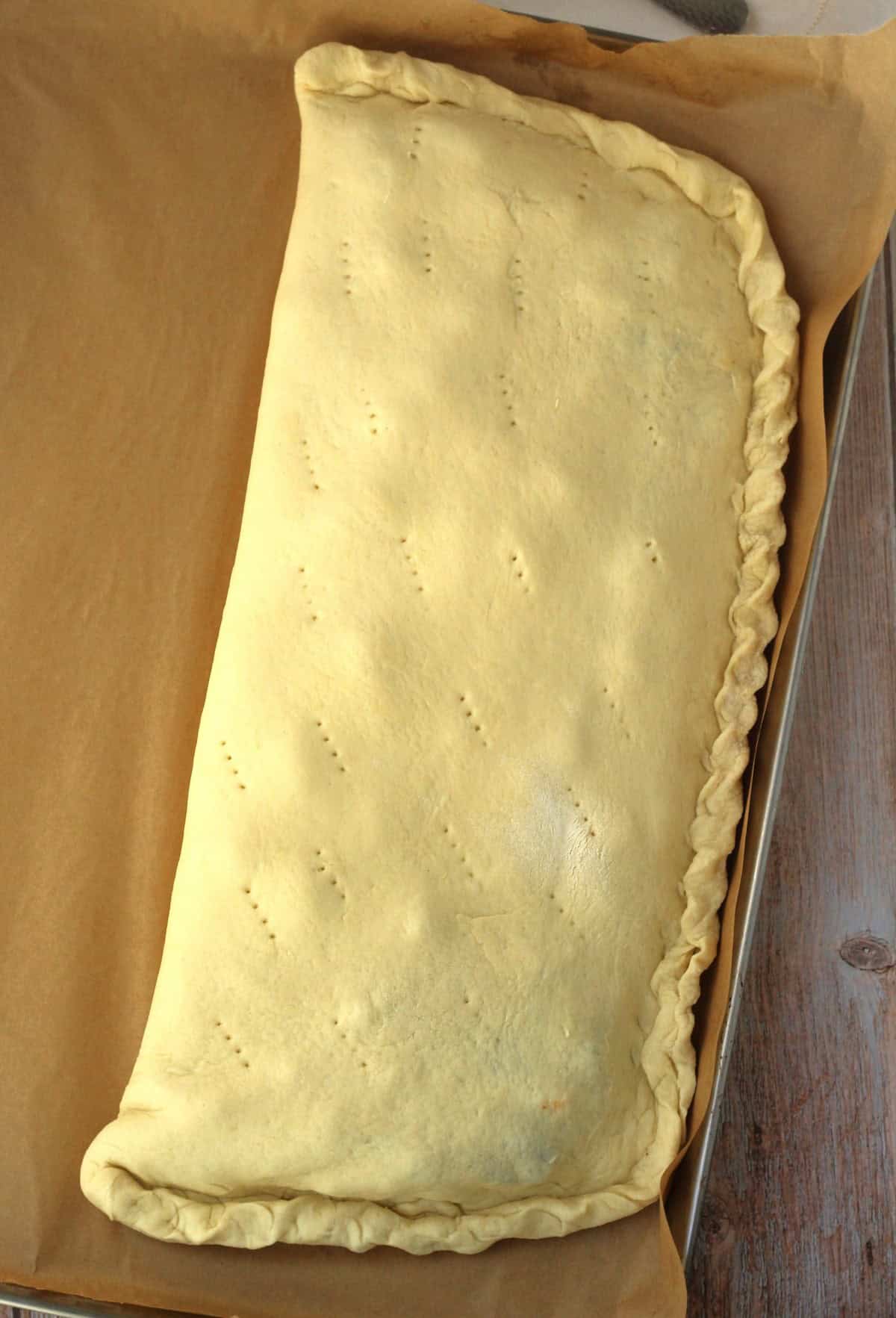 Cudduruni dough folded over filling in half moon shape with edges crimped and pricked with small holes.