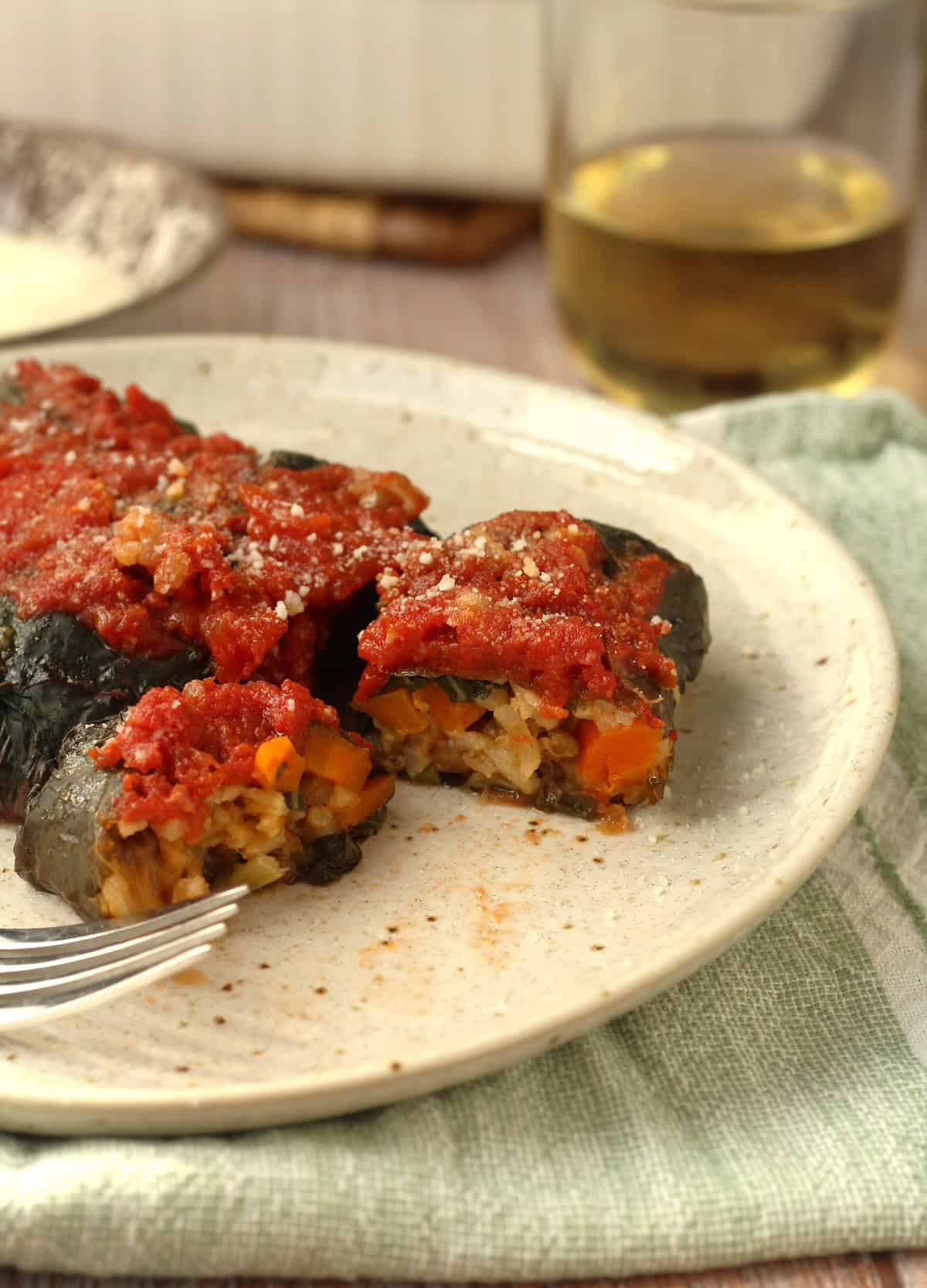 Swiss chard rolls filled with rice and lentils cut open on plate with fork.