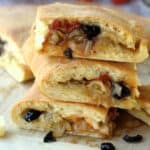 Sicilian cudduruni squares with onion and black filling piled on one another.