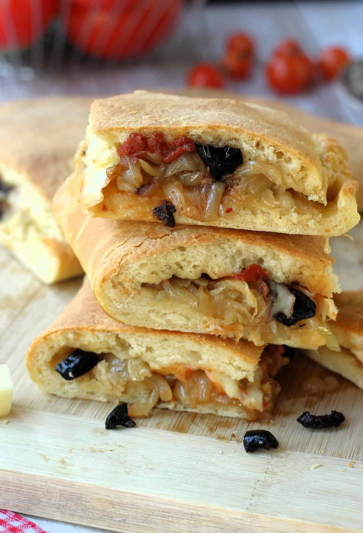 Sicilian cudduruni squares with onion and black filling piled on one another.