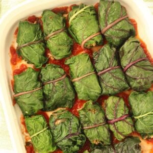 Swiss chard rolls filled with lentils and rice side by side in casserole dish.