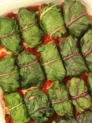 Swiss chard rolls filled with lentils and rice side by side in casserole dish.