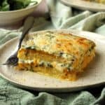 Butternut squash and spinach polenta lasagna on plate with fork.