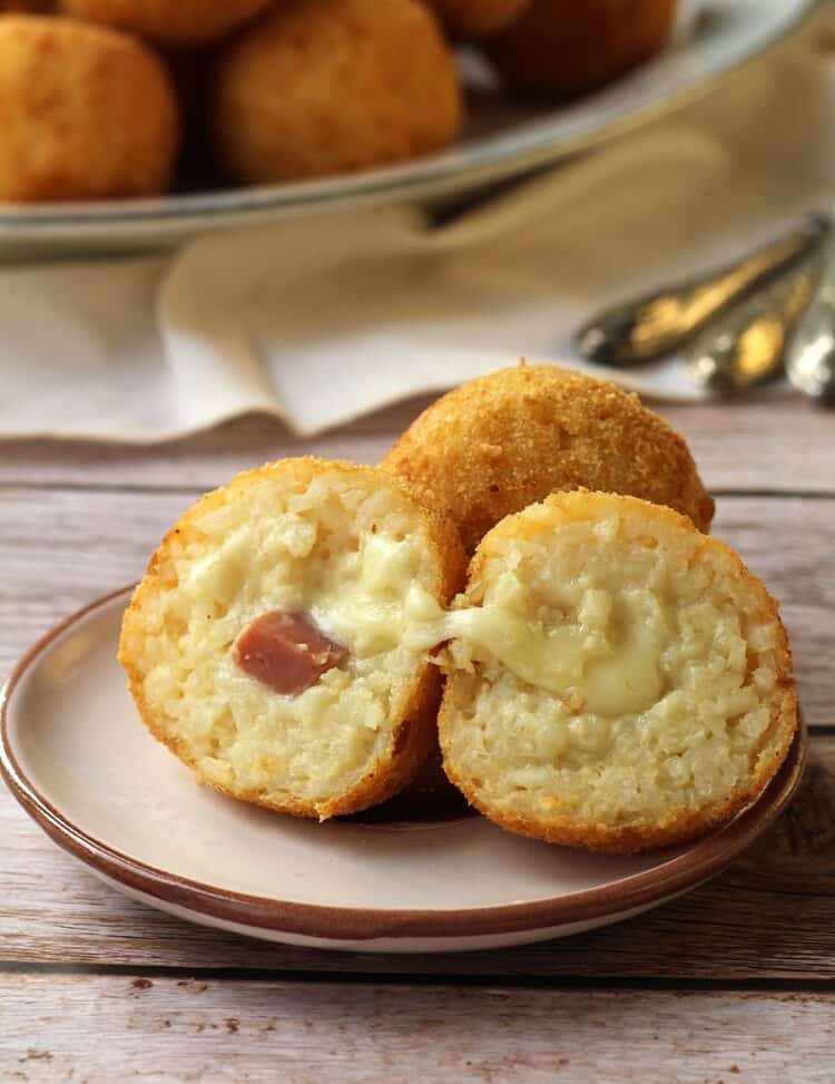 Ham and cheese arancini cut open on plate.