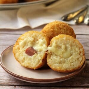 Ham and cheese arancini cut open on round plate.