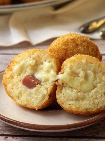 Ham and cheese arancini cut open on round plate.