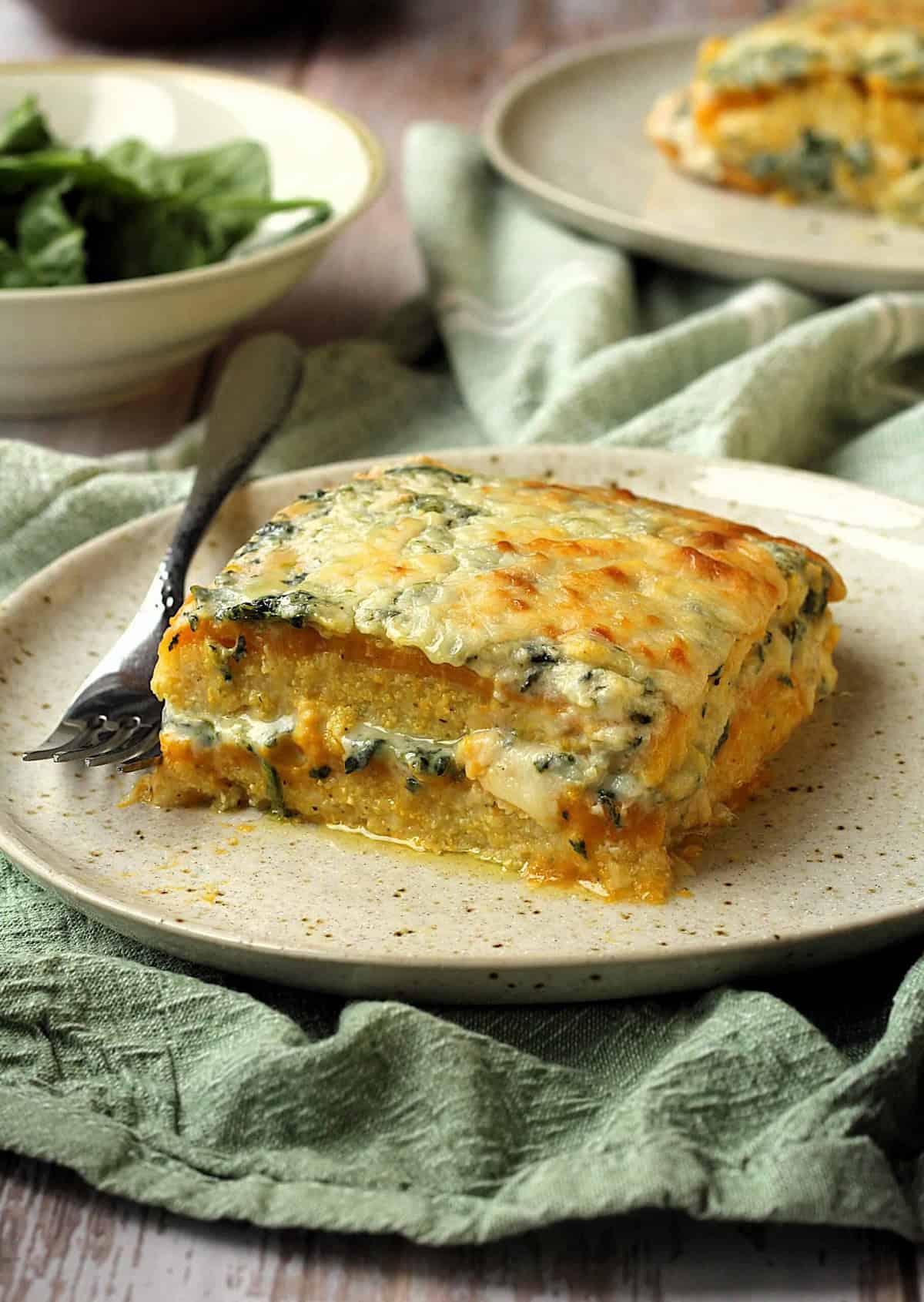 Butternut squash and spinach polenta lasagna on plate with fork.