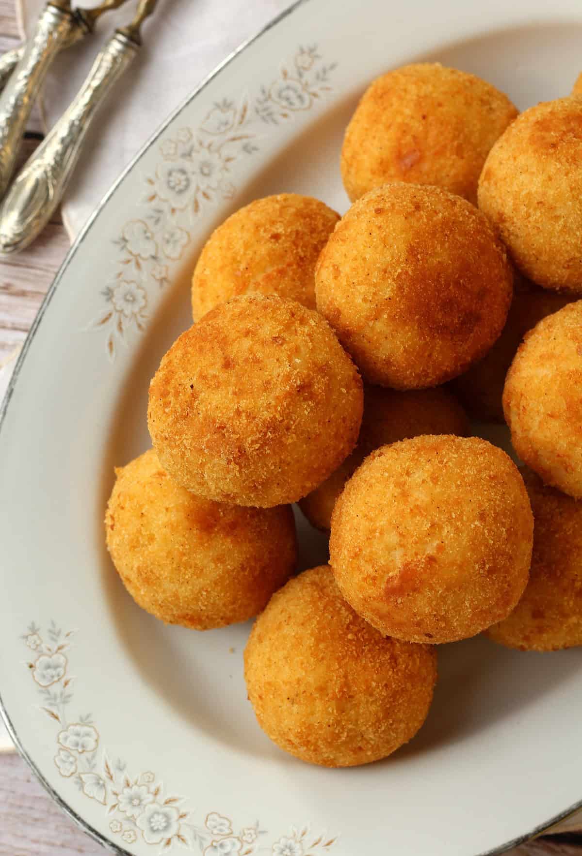 Arancini with ham and cheese (arancini al burro) piled on oval platter.
